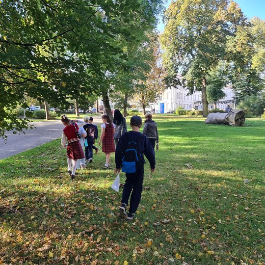 Gedimino kalno papėdėje esančiame parke vaikai mokosi orientuotis. Aplink dar žaliuoja medžiai, tačiau ant pievelės jau nukritę geltoni lapai. Vaikai nusisukę nuo kameros, eina Katedros link. Pro medžius matosi kampelis Valdovų rūmų.