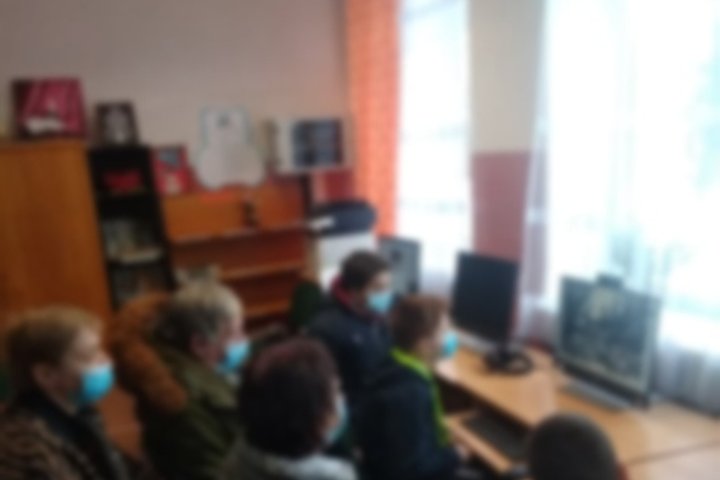 Bagaslaviškio dienos centro lankytojai žiūri į ekraną ir klausosi paskaitos apie Vilniaus pilis.