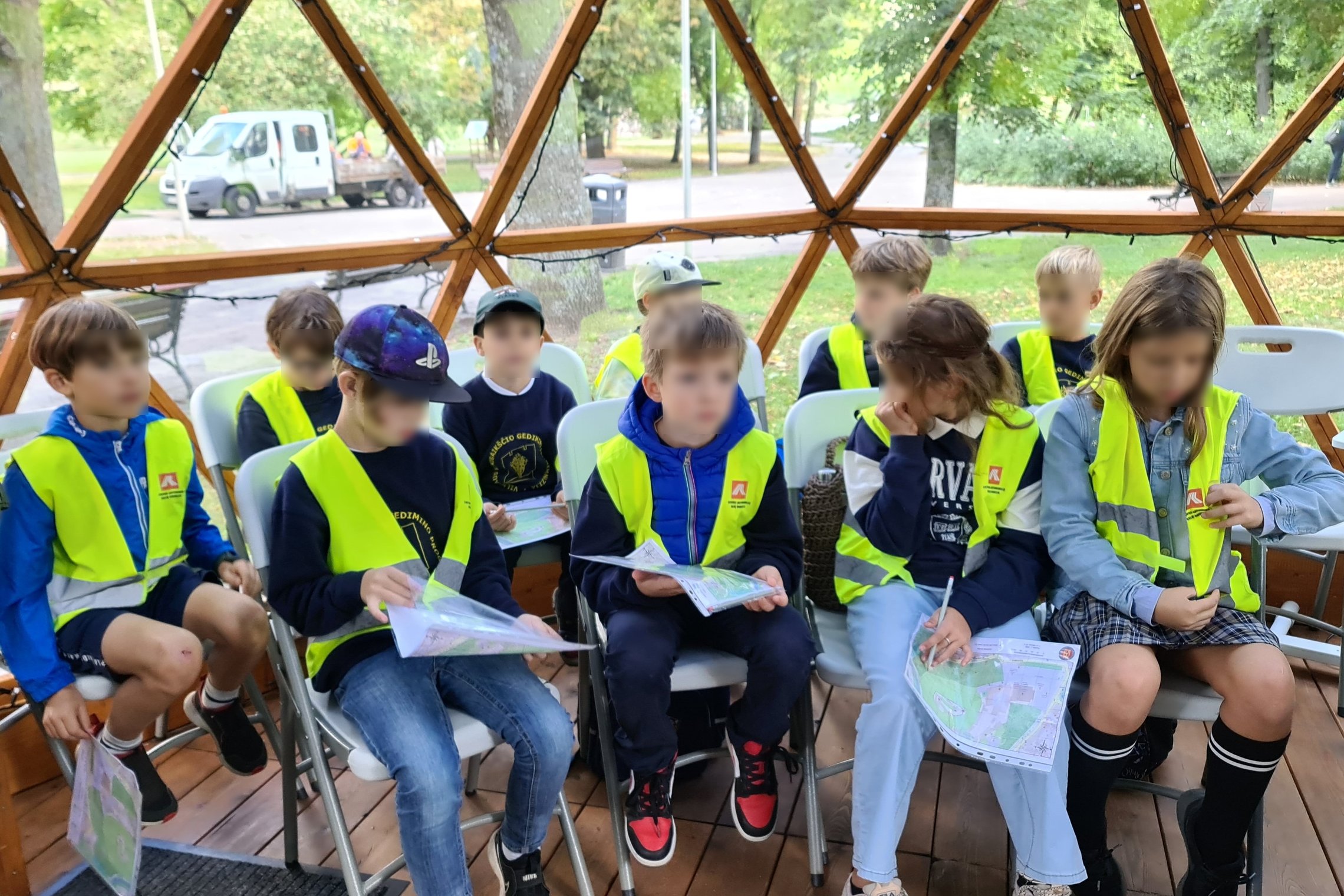 Mokiniai tyrinėja VIlniaus pilių planus kupole, klausydamiesi instruktažo.