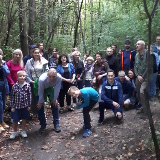 Žaliame miške pozuoja įvairaus amžiaus ekskursijos dalyviai. Jie keliauja su Vilniaus pilių gidu.