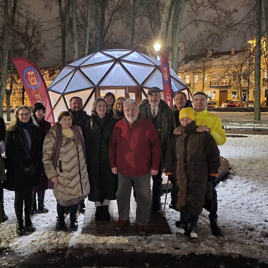 Tamsus vakaras. Prie Gedimino kalno papėdėje esančio Vilniaus pilių kupolo nuotraukai pozuoja sustoję edukacijos dalyviai. Priekinėje eilėje stovi profesorius Alfredas Bumblauskas.