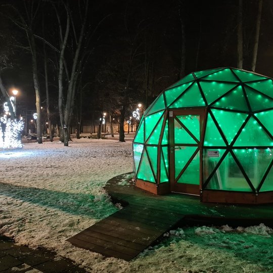 Vilniaus pilių kupolas šviečiantis žaliai, nufotografuotas iš lauko. Vakaras, aplink apsnigta. Kupolas nufotografuotas iš priekio.