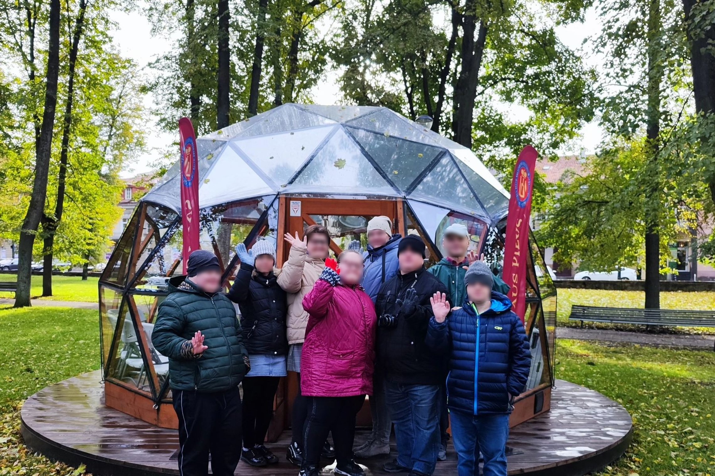 Giedra diena. Fone medžiai jau meta lapus. Prieš Vilniaus pilių kupolą sustoję Markučių dienos centro lankytojai šypsosi ir mojuoja kamerai.