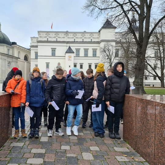 Mokiniai su užduočių lapais prie miesto buvusių vartų Katedros aikštėje.
