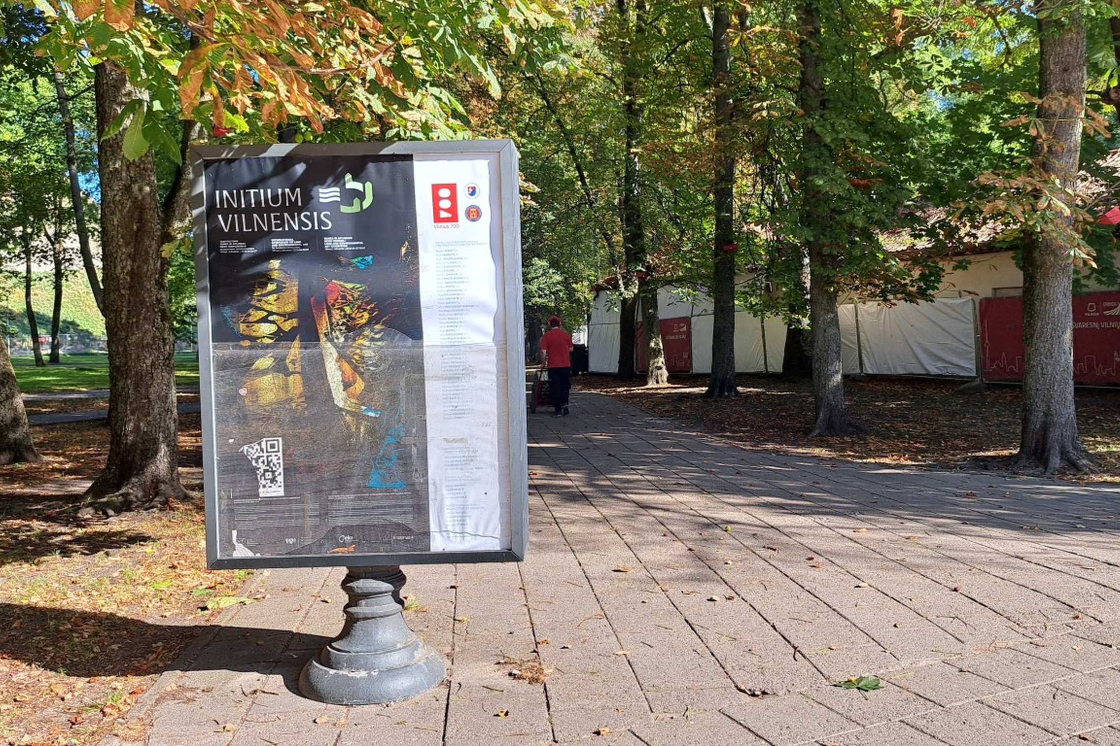 Nuotraukoje stovi reklamos skydas. Jame reklamuojama paroda Initium Vilnensis - žemės ir aplinkos menas, kuris buvo eksponuojamas Vilniaus pilių teritorijoje. 