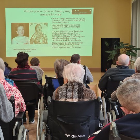 Edukacijos dalyviai klausosi paskaitos salėje.