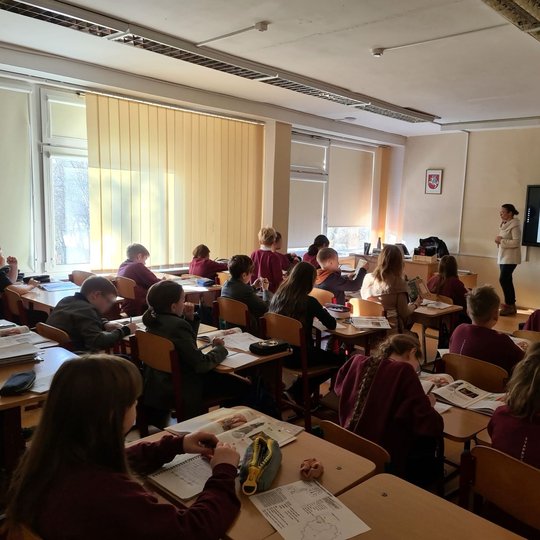Penktokai klasės suoluose klausosi pamokos apie Gediminaičius.