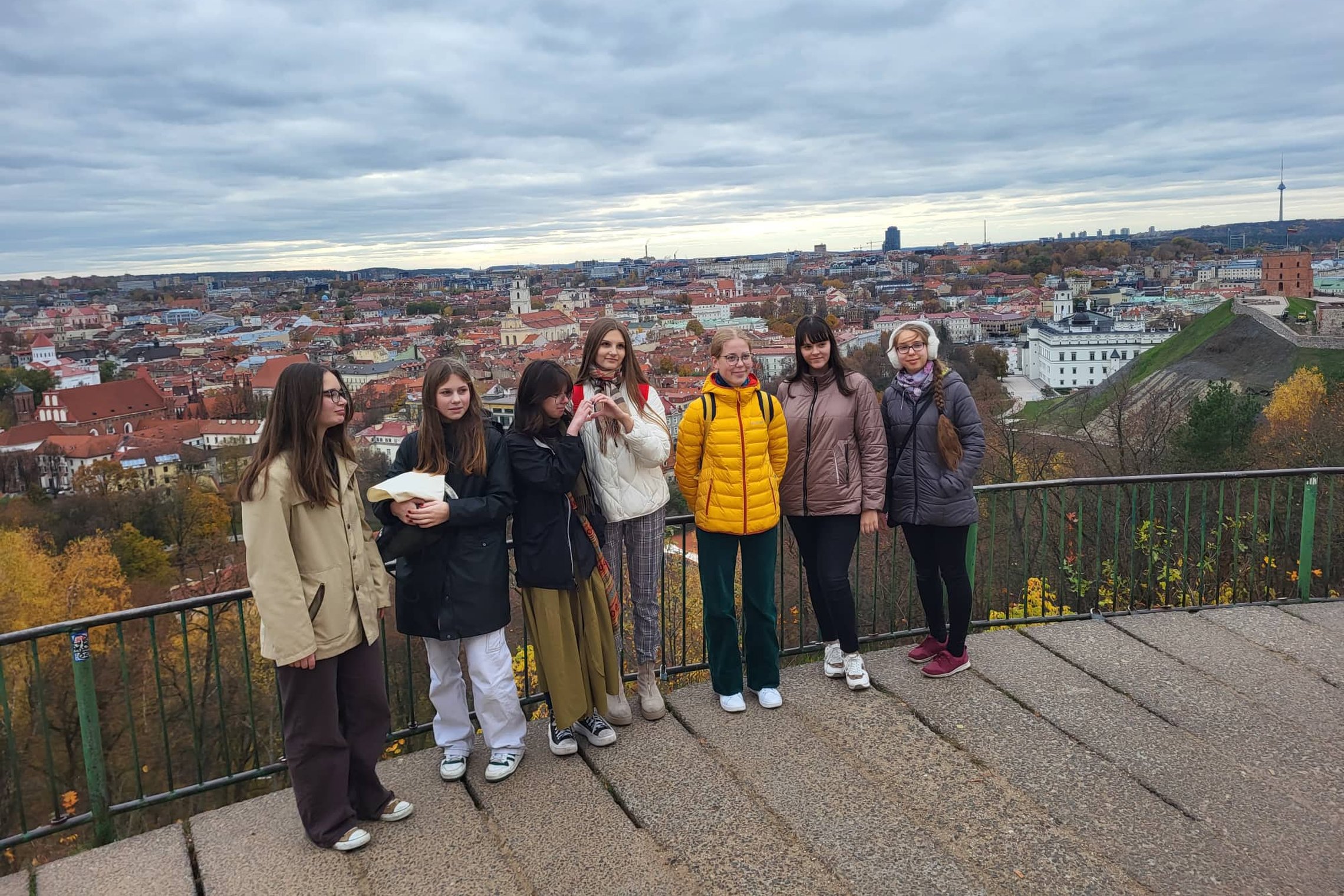 Būrelio nariai pozuoja nuotraukai nuo Trijų Kryžių kalno. Už nugarų matosi Vilniaus panorama.