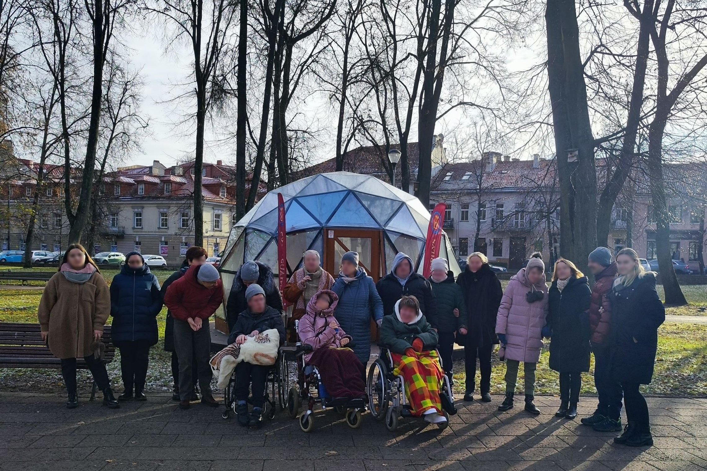Grupė į ekskursiją atvykusių žmonių, išsirikiavę prie Vilniaus pilių kupolo.
