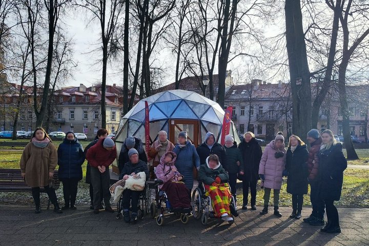 Grupė į ekskursiją atvykusių žmonių, išsirikiavę prie Vilniaus pilių kupolo.