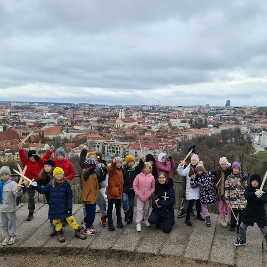 Mokinių grupė pozuoja sustoję ant Trijų kryžių kalno apžvalgos aikštelės.