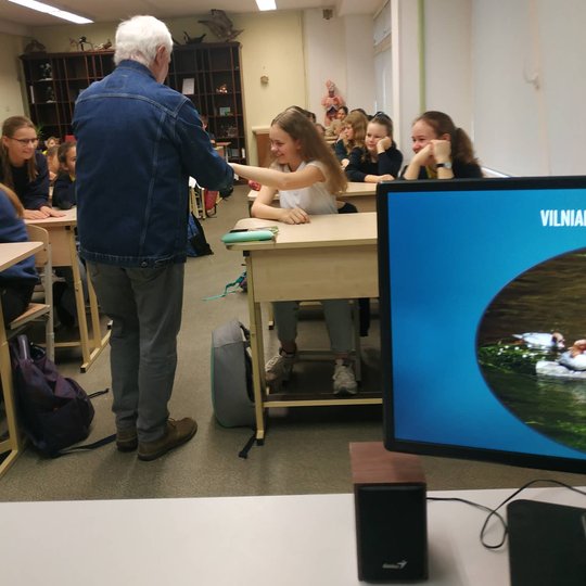 Edukatorius Stasys su balandžiu rankose vaikšto po klasę.