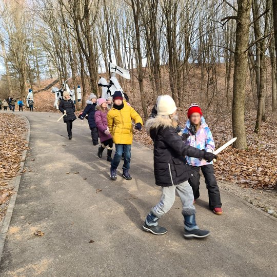 Moksleiviai keliauja po Kalnų parką su mediniais kardais rankose.
