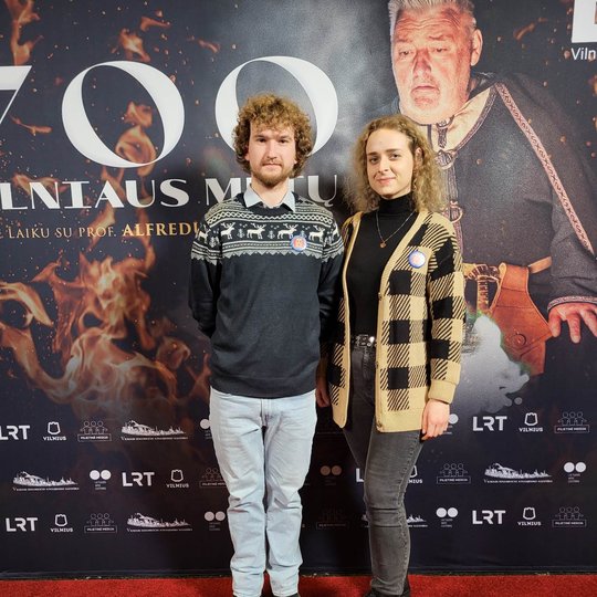 Vilniaus pilių rezervato atstovai pozuoja nuotraukai šalia filmo afišos.