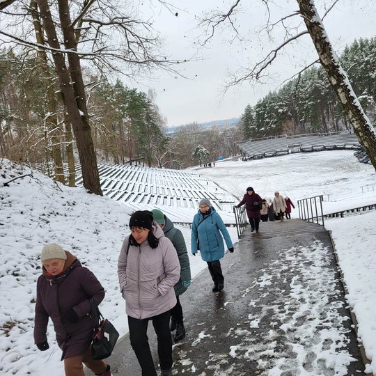 Eskursantai taku eina nuo Dainų slėnio estrados link Karigailos kalvos. Aplink apsnigtos pievos.