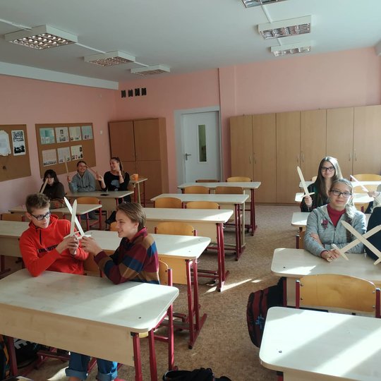 Aštuntokai su mediniai kalavijais rankose pozuoja nuotraukai klasėje.