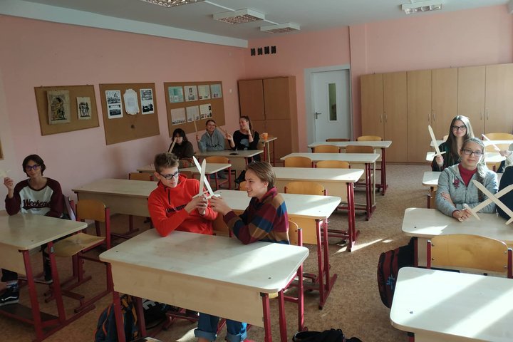 Aštuntokai su mediniai kalavijais rankose pozuoja nuotraukai klasėje.