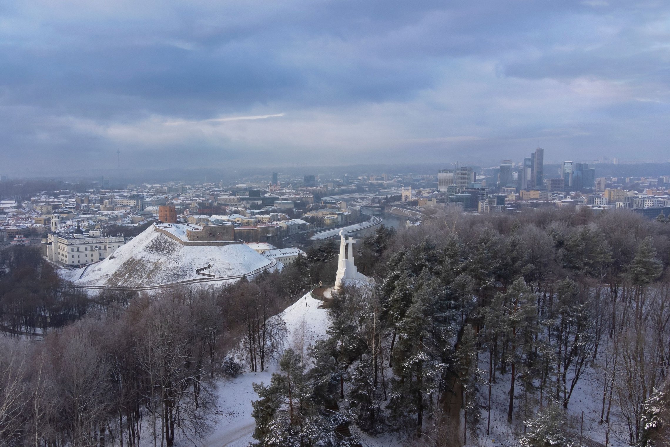 Apsnigtas Vilniaus pilių rezervatas diena. Nuotraukoje matosi Trijų Kryžių paminklas ir kalva bei Gedimino kalnas su bokštu. Tolumoje Vilniaus miesto panorama.