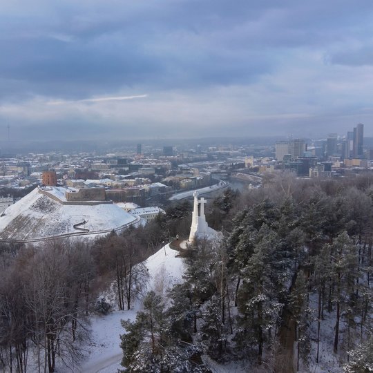 Apsnigtas Vilniaus pilių rezervatas diena. Nuotraukoje matosi Trijų Kryžių paminklas ir kalva bei Gedimino kalnas su bokštu. Tolumoje Vilniaus miesto panorama.