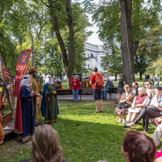 Keturi žmonės, persirengę Kernavės didikais prie kupolo.