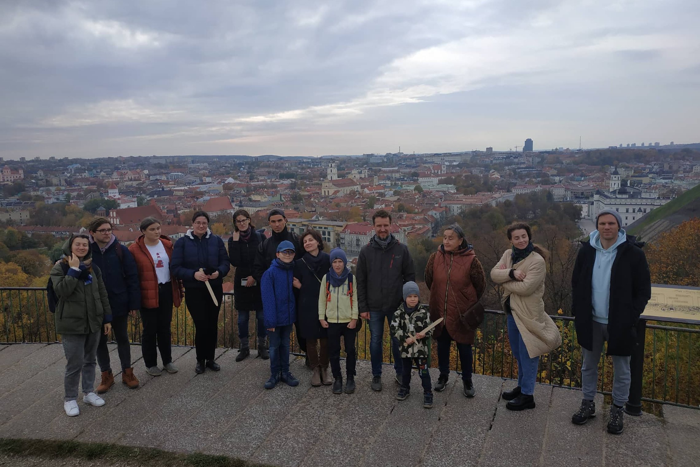 Ekskursijos dalyviai pozuoja nuotraukai ant Trijų Kryžių kalvos. Ekskursantams už nugarų Vilniaus miesto panorama.
