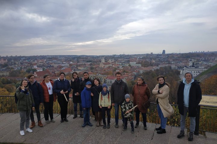 Ekskursijos dalyviai pozuoja nuotraukai ant Trijų Kryžių kalvos. Ekskursantams už nugarų Vilniaus miesto panorama.