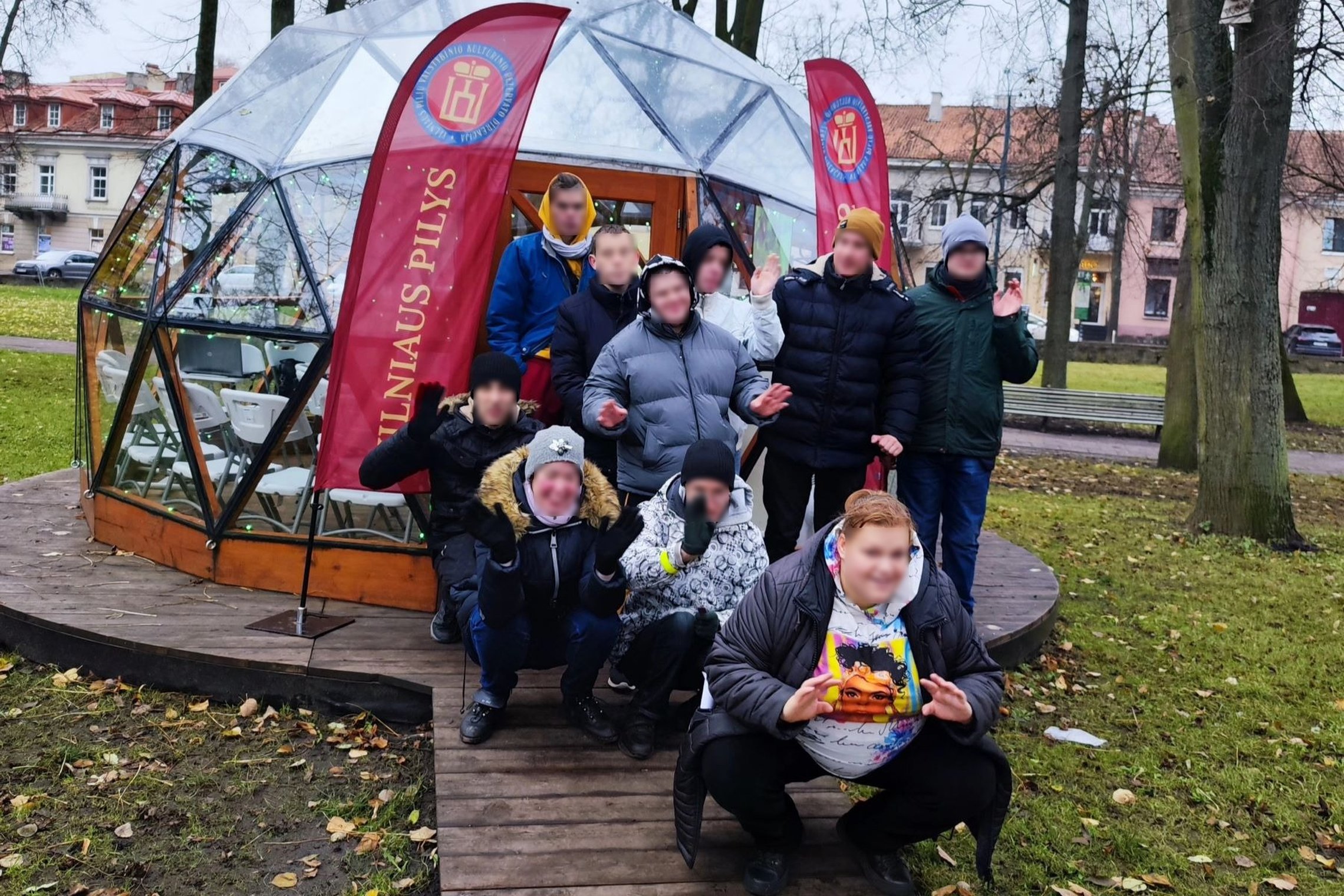 Vilniaus Vilties mokyklos auklėtiniai mojuoja ir pozuoja prie Vilniaus pilių kupolo. Visi nusiteikę žaismingai.