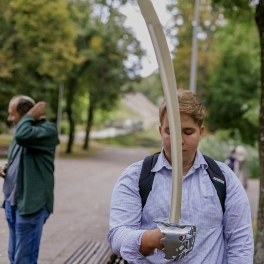 Vienas iš paskaitos klausytojų laiko kardą ir jį tyrinėja.