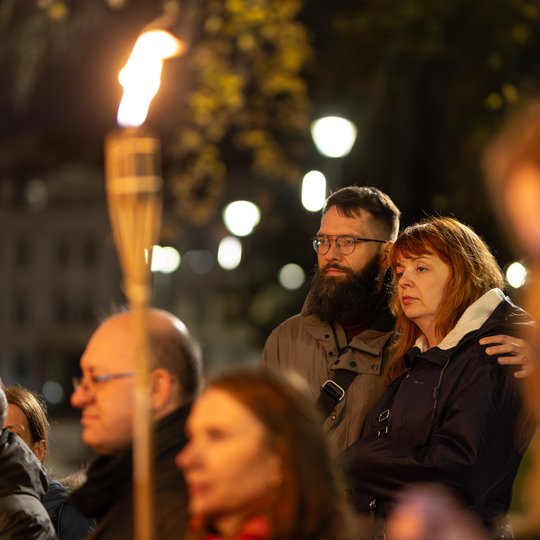 Pora ekskursijos dalyvių susidomėję klausosi pasakojimo. Nuotraukoje matosi ir degantis fakelas.