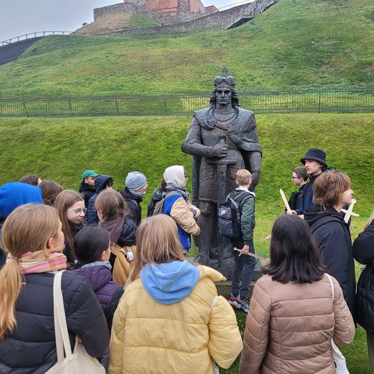 Penktokai klausosi pasakojimo apie Vytautą šalia jo statulos.
