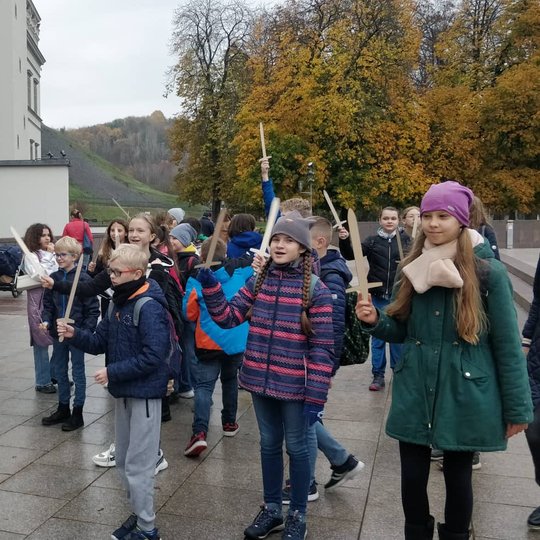 Mokiniai su mediniai kalavijai rankose šalia Valdovų rūmų vartų.