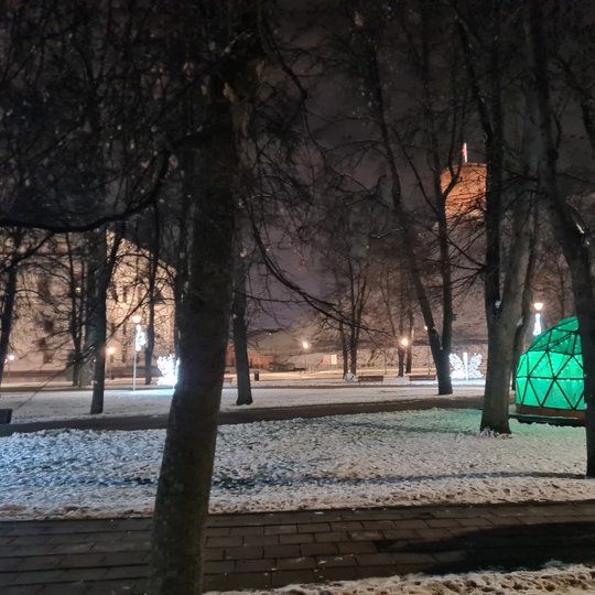 Sereikiškių pilių parkas žiemos vakarą. Nuotraukoje matosi žaliai švenčiantis Vilniaus pilių kupolas, Valdovų rūmais bei Gedimino kalnas su bokštu.