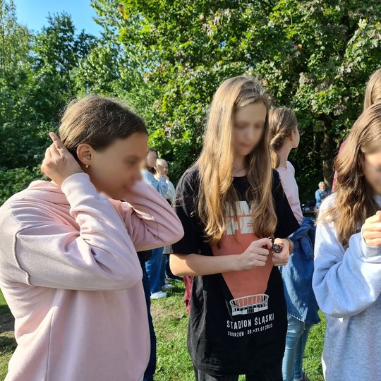 Nuotraukoje mergaitės išbando, kaip užkurti ugnį, naudojantis skiltuvu.