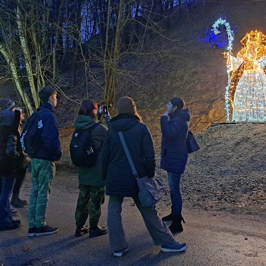 Gidė pasakoja, o mokiniai klausosi ekskursijos. Už jų - Lizdeikos instaliacija.