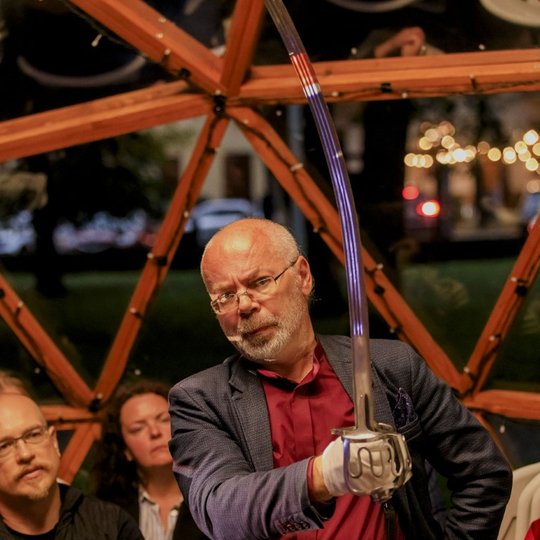 Demonstruojamas kardas su puoštu furdimentu.