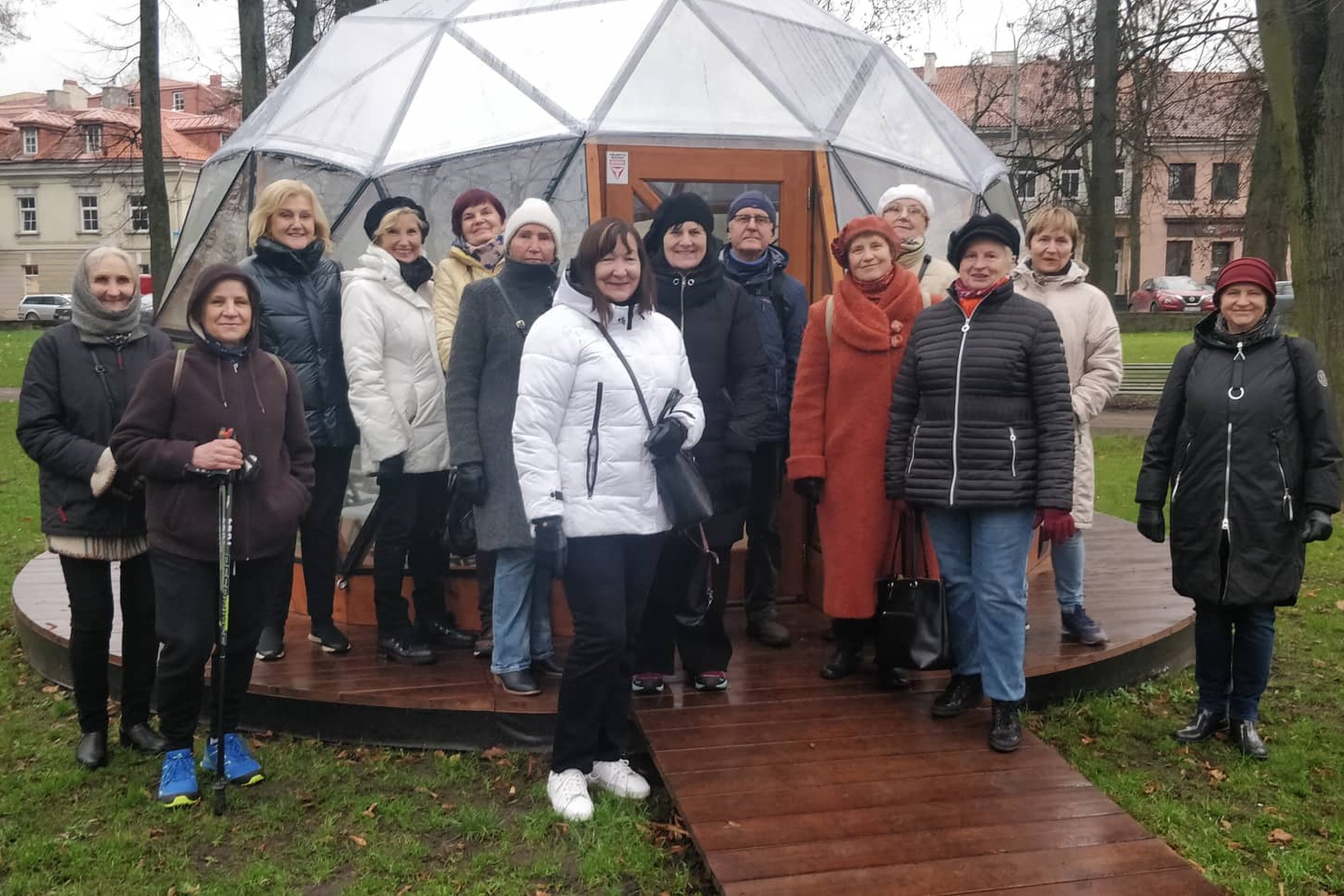 Trečiojo amžiaus universiteto nariai pozuoja nuotraukai priešais Vilniaus pilių kupolą.