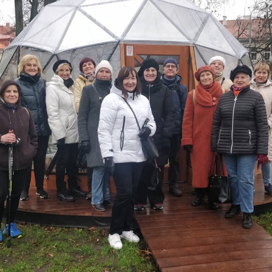 Trečiojo amžiaus universiteto nariai pozuoja nuotraukai priešais Vilniaus pilių kupolą.