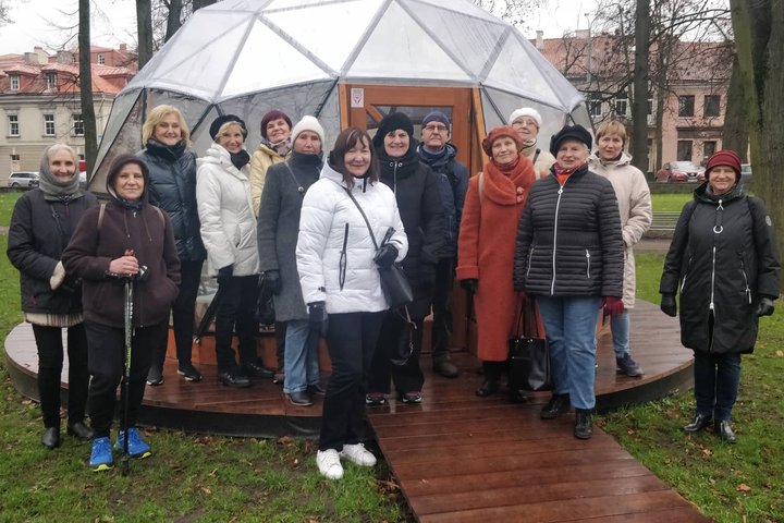 Trečiojo amžiaus universiteto nariai pozuoja nuotraukai priešais Vilniaus pilių kupolą.