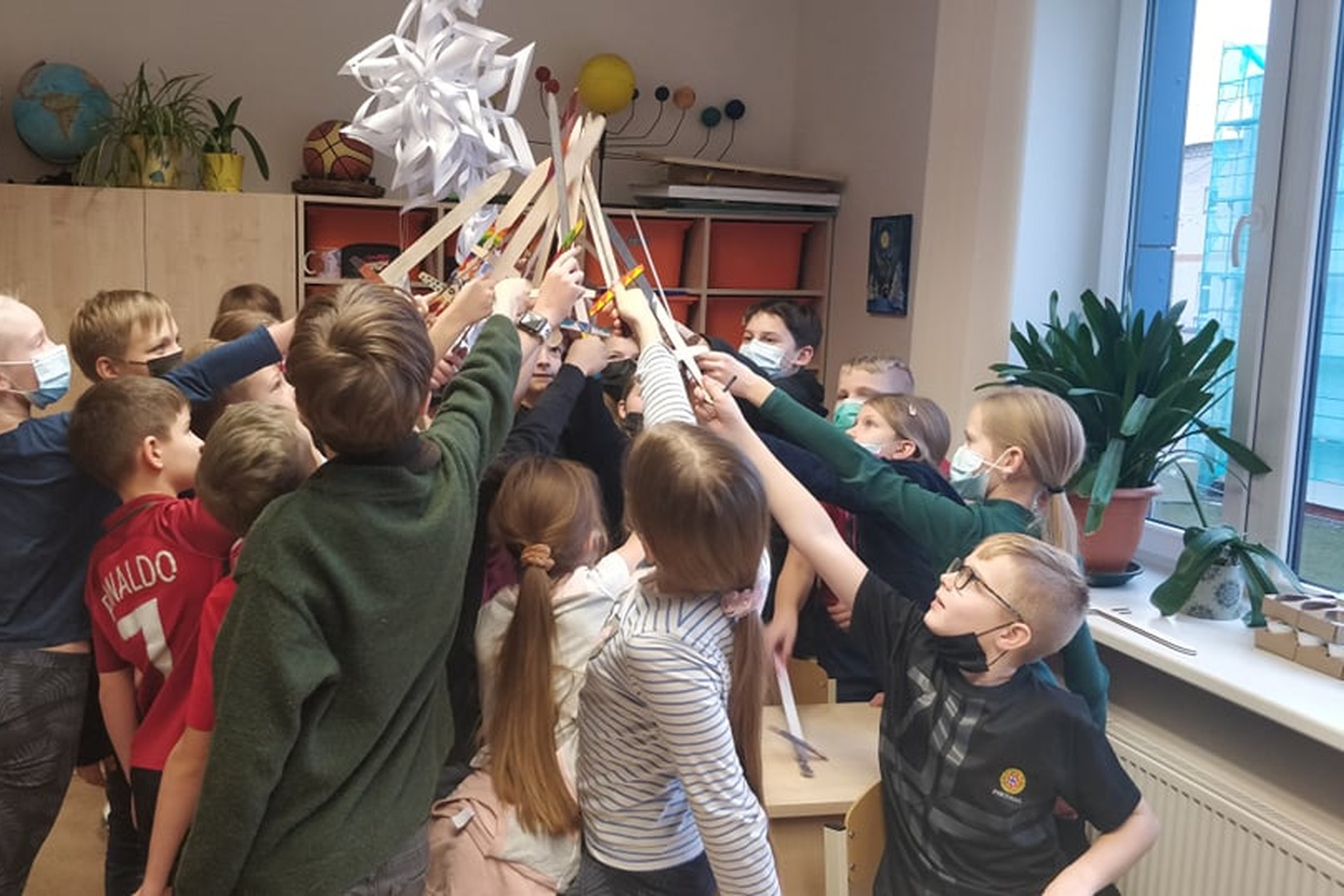 Vaikai klasėje sustoję ratu ir iškėlę medinius kalavijus į centrą.