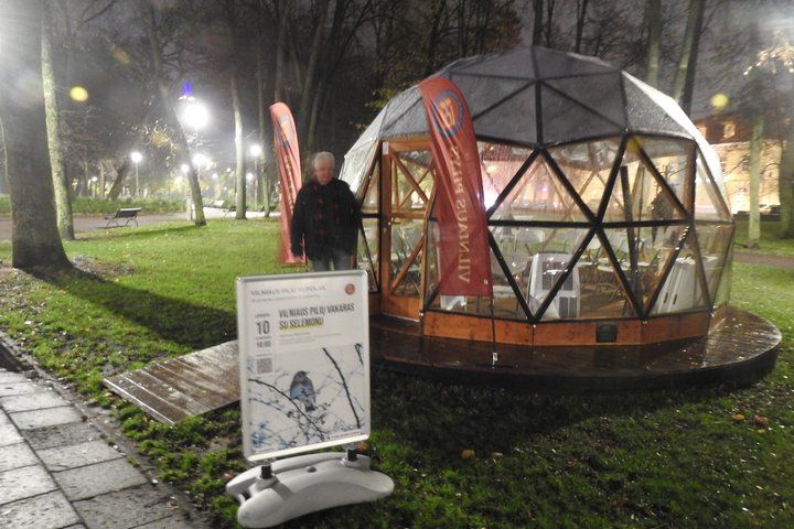 Vilniaus pilių kupolas iš lauko. Priešais kupolą paskaitos afiša. Prie įėjimo stovi aplinkosaugininkas Selemonas Paltanavičius.