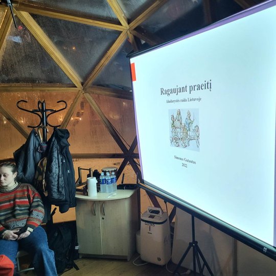 Vilniaus pilių stikliniame kupole stovi projektoriaus ekranas kurioje vaizduojamos skaidrės. Taip pat prie projektoriaus ekrano stovi maža spintelė, ant kurios stovi vandens buteliukai žmonėms atsigerti.