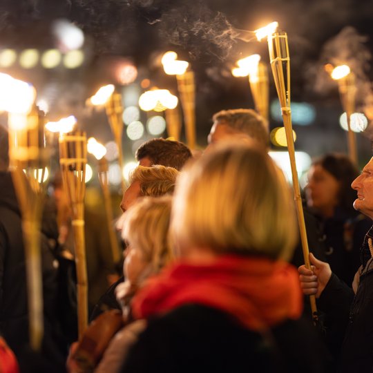 Ekskursijos dalyviai keliauja tamsoje su degančiais fakelais.