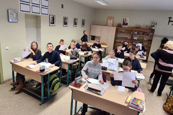 Vaikai klasėje aktyviai varto sąsiuvinius ir baltus lapus.
