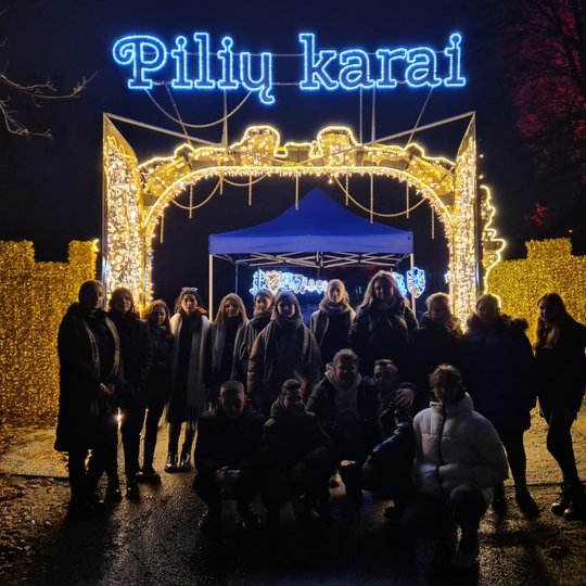 Mokiniai prie instaliacijų parko vartų. Viršuje švyti užrašas "Pilių karai".