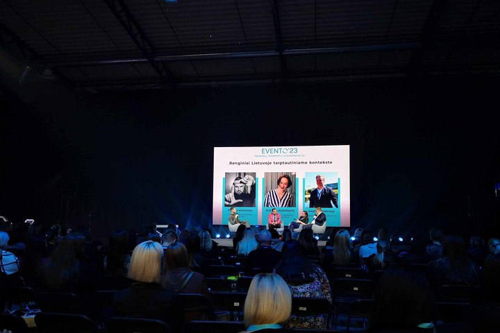 Evento 23 renginyje, auditorijoje, pritemdžius šviesas, per projektorių rodomas pristatymas.