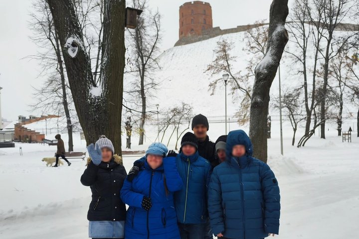 Markučių dienos veiklos centro lankytojai mojuoja iš Pilių parko, už jų matosi Gedimino pilies kalnas ir bokštas.