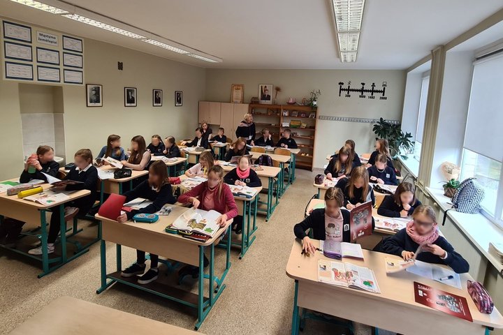 Penktokai sėdi klasės suoluose ir varto istorijos vadovėlius.