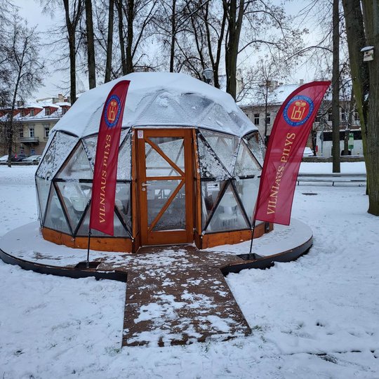 Vilniaus pilių kupolas iš lauko. Šalia įėjimo pastatytos  Vilniaus pilių rezervato vėliavos. Aplink apsnigta.