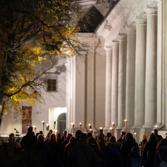 Būrys žmonių keliauja su fakelais pro Katedros aikštę Mindaugo skvero link.