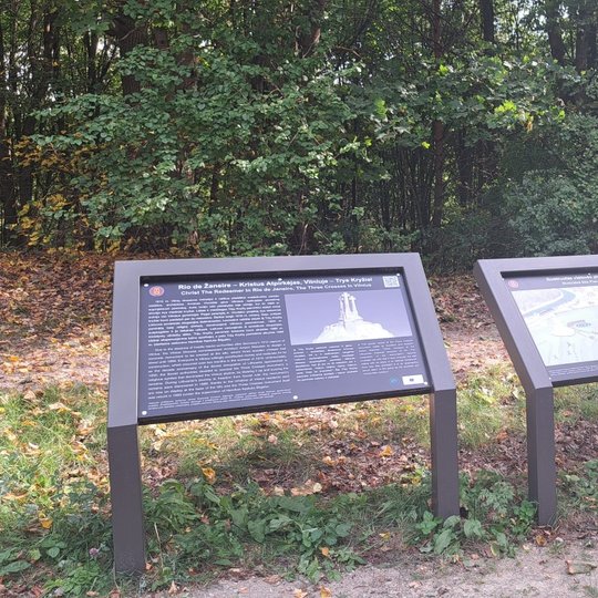 Nuotraukoje vaizduojami trys stendai, kuriuose yra pavaizduotas bei aprašytas Trijų Kryžių kalnas. Taip pat yra matomas keliukas, kuris veda į dešinę pusę nuo stendų.